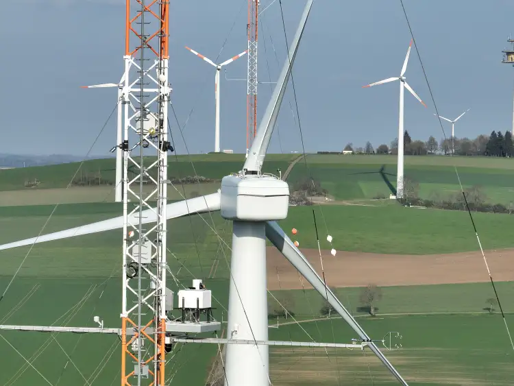 Lidarsystem auf der Plattform eines meteoroligschen Messmastes in Nabenhöhe. Im Hintergrund sind die Gondel und der Rotorstern der Forschungswindenergieanlage zu sehen.